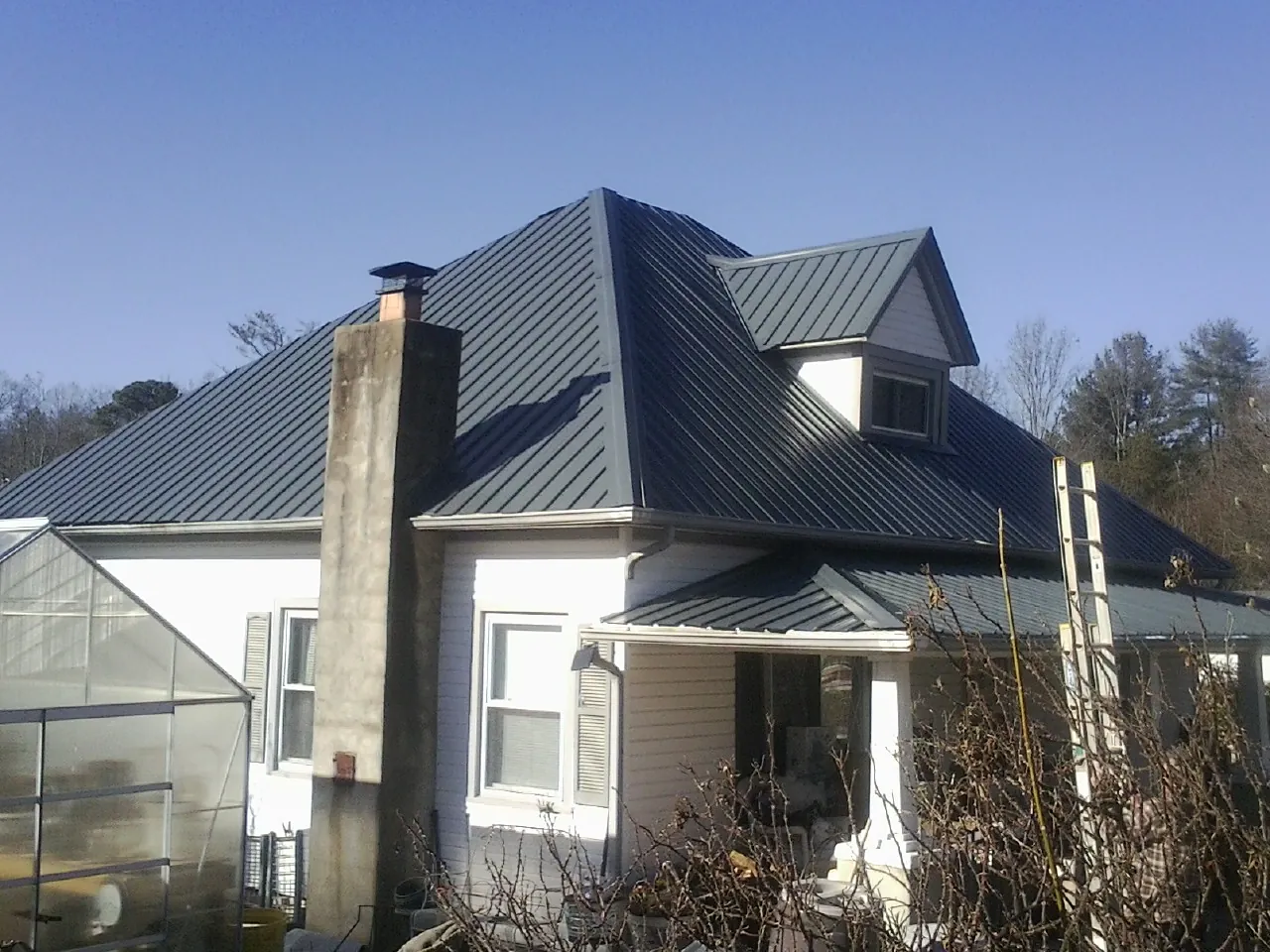 Dark blue standing seam metal roof on a white farmhouse with dormer — Slate & Tile Roof Repair by Roofing Brothers in Antioch