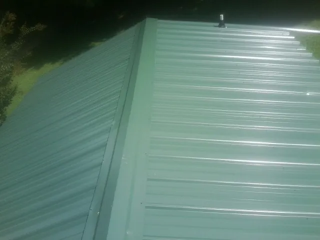New green metal panels meeting at the ridge of a roof — Flat Roof Repair work by our crew in Antioch