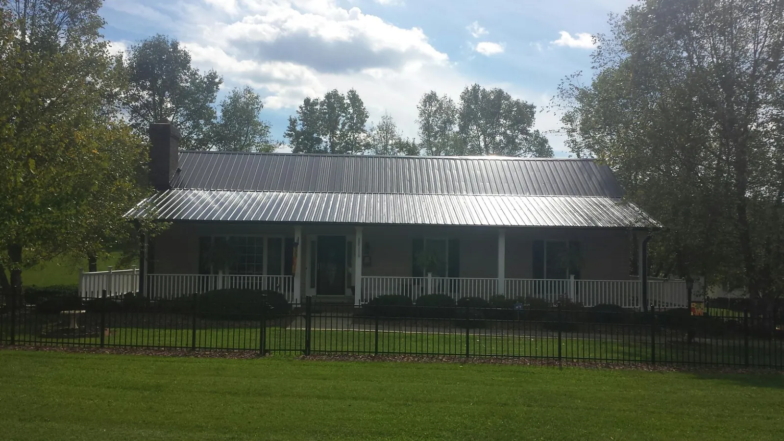 Gray metal roof on a brick ranch with a full width front porch — Gutter Guard Installation work by our crew in Antioch